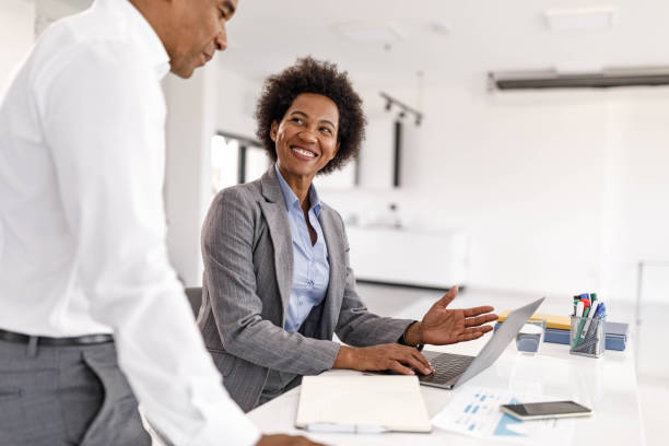 istock Happy black business colleagues talking while working on laptop in the office. 2187968103