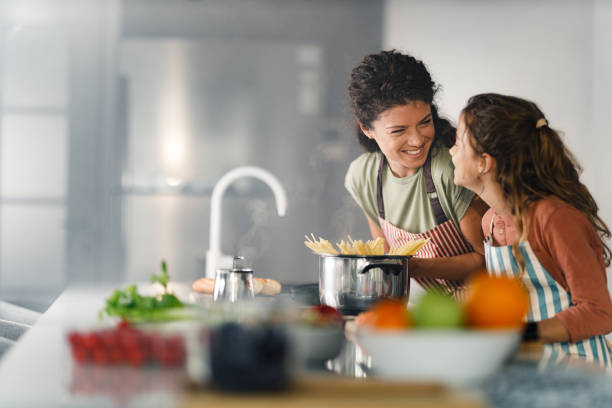 istock Happy mother and daughter talking while making lunch in the kitchen. 2187968593