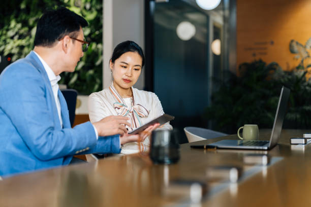 istock Asian business colleagues discussing documents on digital tebalet in a modern office. 2187976046