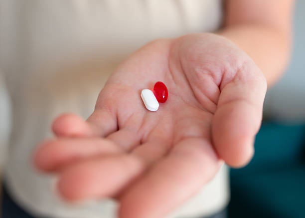 istock Close-up of a man's hand holding two pills red and white 2187979892