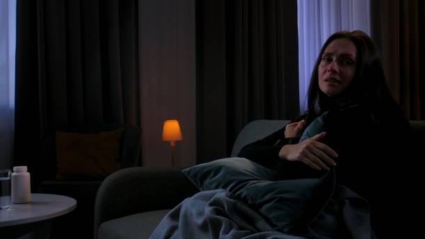 istock Woman suffering mental health issues, sitting on sofa covered in blanket, depressed expression, looks at side, upset face and hugging pillow, side view. 2187981212