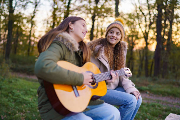 istock Girls having fun playing guitar in the forest 2187984781