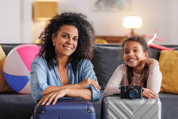 istock A mother and her daughter sit on the floor, comfortably leaning on their suitcases, ready for a fun vacation ahead 2187986471