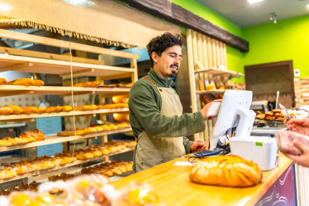 istock Salesman using touchscreen computer in the counter of bakery shop 2187987155