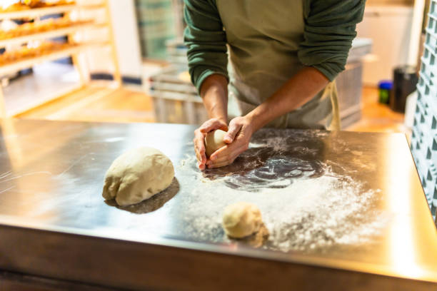 Close-up of hands of a baker kneading dough at workshop