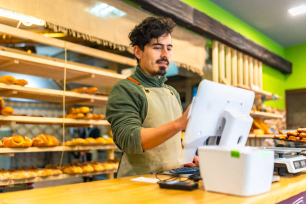 istock Salesman using touchscreen computer in the counter of bakery shop 2187987237