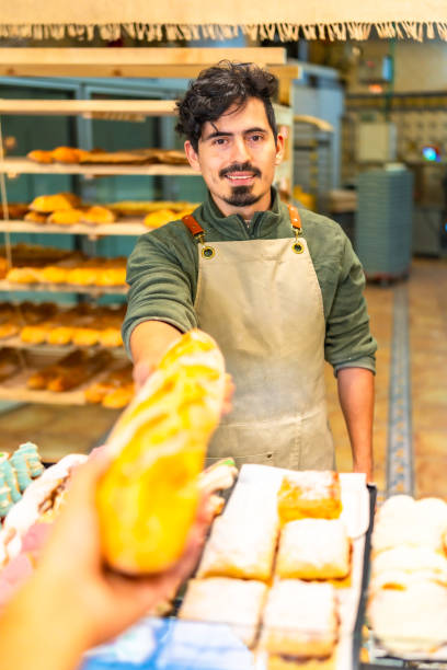 istock Man selling baguette to a client in the bakery shop 2187987265