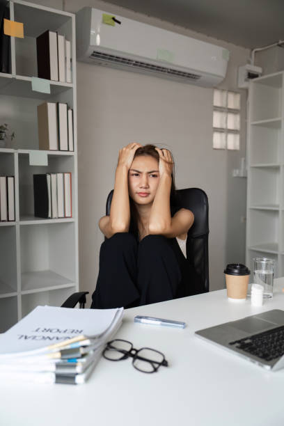 istock Stressed Office Worker Sitting at Desk with Documents and Laptop in Modern Workspace 2187987641