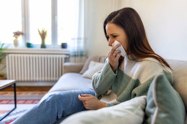 istock Woman Sneezing on Sofa at Home with Tissues During Daytime 2187988849