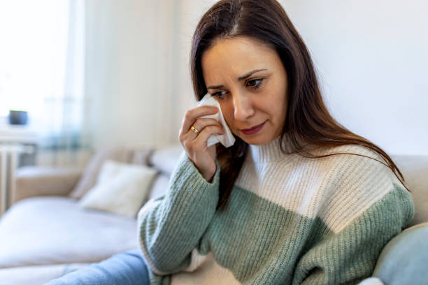 Woman Wiping Tears While Sitting Alone on a Couch at Home