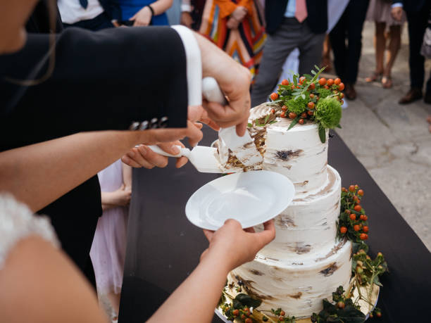 Cutting Rustic White Wedding Cake with Orange Berry Decorations