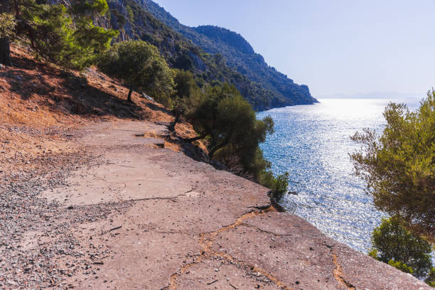 Old broken abandoned road goes over rocky sea coast on a sunny summer day. Coastal Mediterranean landscape photography taken near Iztuzu Beach, Turkey