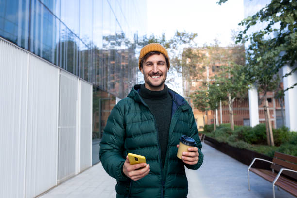 istock Young man using smartphone and holding coffee walking in the city 2187991623