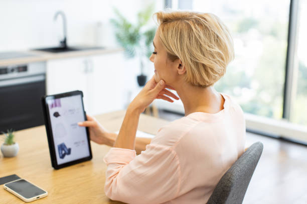 istock Caucasian woman shopping online using a tablet in modern home 2187991904