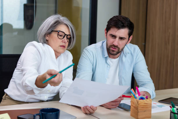 istock Businesswoman explaining a document to a businessman in a coworking space 2187992540