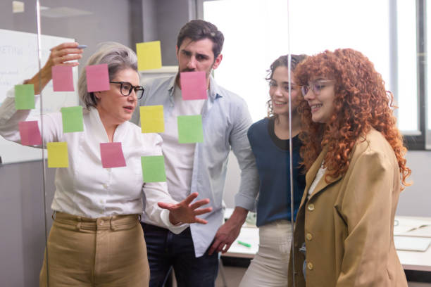 istock Business team brainstorming with sticky notes on glass wall in coworking space 2187992895