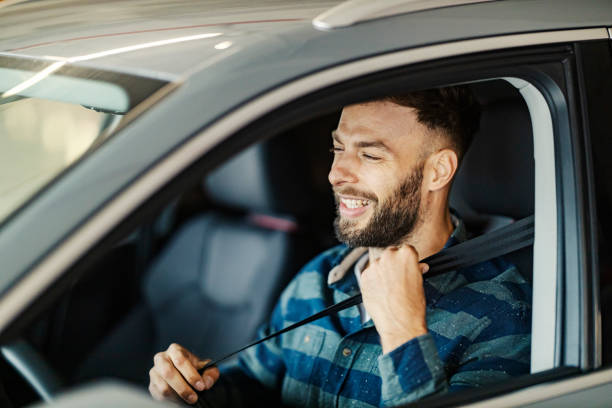 istock Happy responsible casual man putting seat belt while sitting in his car. 2187993232
