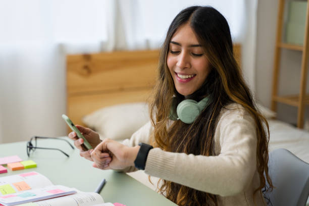 istock woman checking time on smartwatch while using smartphone at home 2187993581