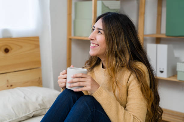 istock woman smiling and holding a mug in her bedroom 2187993698