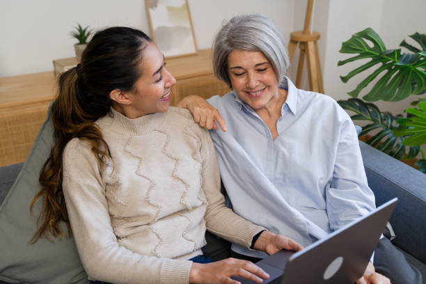 istock Smiling women using laptop on sofa at home 2187994387