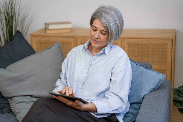 istock Mature woman using digital tablet on sofa at home 2187994962
