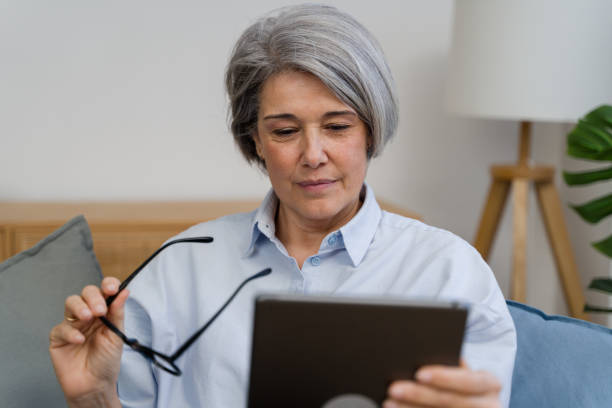 istock Senior woman using digital tablet at home: holding eyeglasses 2187995023