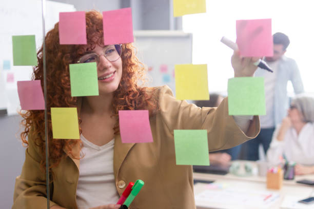 istock Young businesswoman writing on sticky notes during a brainstorming session 2187995785