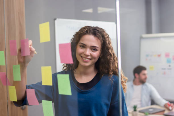 istock Young businesswoman writing notes on sticky notes in coworking space 2187996471