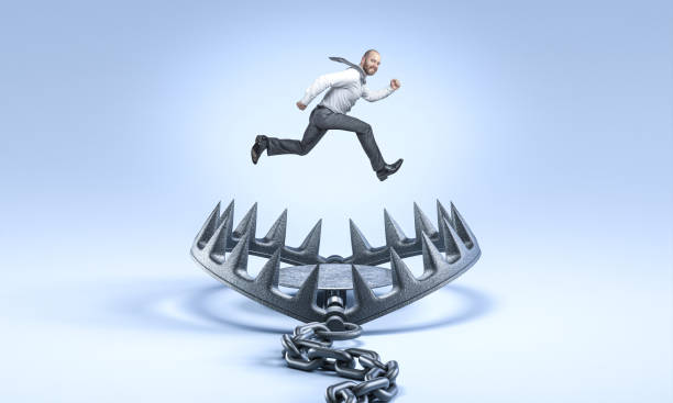 istock Businessman jumping over a bear trap in a blue background 2187996533