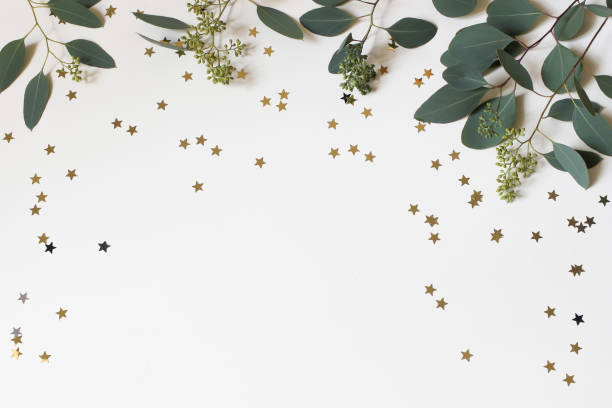 istock Christmas, New Year decorative frame, web banner. Green eucalyptus tree leaves branches, golden stars shaped confetti isolated on white table background. Winter festive decoration. Flat lay, top view. 2187996641