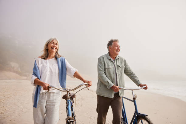 istock Cheerful senior couple walking along beach with bicycles 2187998266