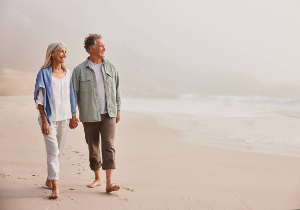 Affectionate senior couple walking and holding hands on beach