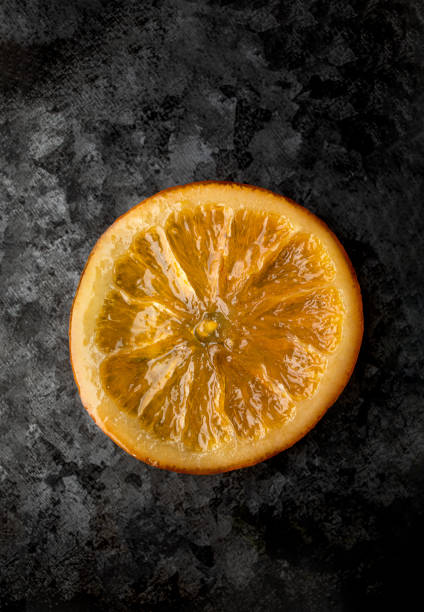 Clove-studded orange tied with red ribbon suspended against white background, evoking festive and aromatic ambiance.