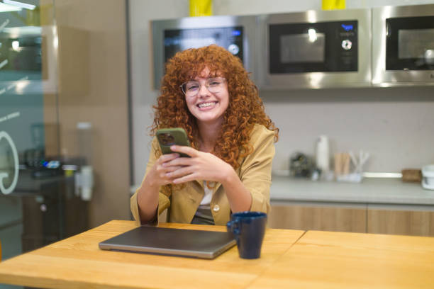 istock Happy businesswoman using smart phone in office kitchen 2188012119