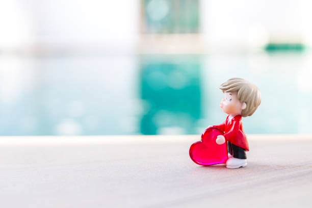 Miniature boy in red suit with red heart over blurred background, outdoor day light, valentine background idea