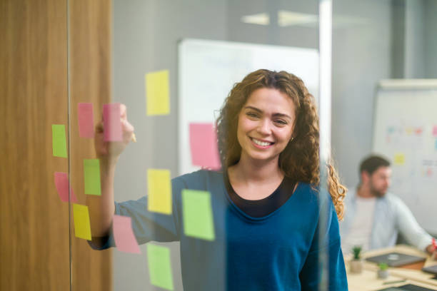 istock Young businesswoman writing on sticky notes during a brainstorming session 2188012183