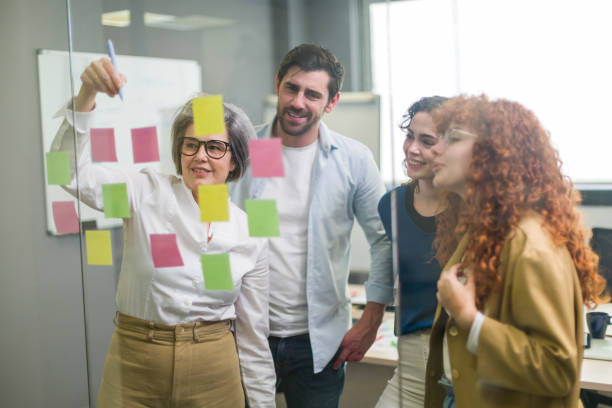 istock Business team brainstorming with sticky notes on glass wall in office 2188012211