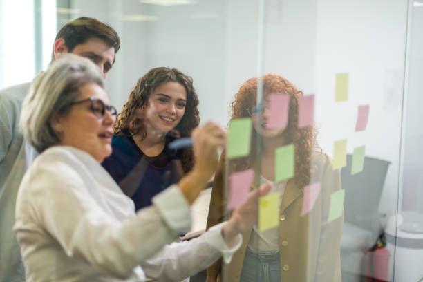 istock Business team brainstorming with sticky notes on glass wall in office 2188012212