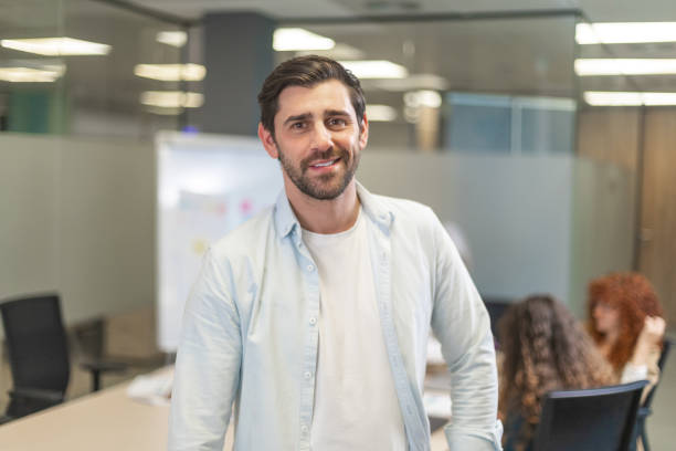 istock Confident businessman smiling in modern office with colleagues working 2188012243