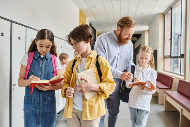 istock Engaging teacher interacts with students while they explore their books in vibrant school hallway 2188016007