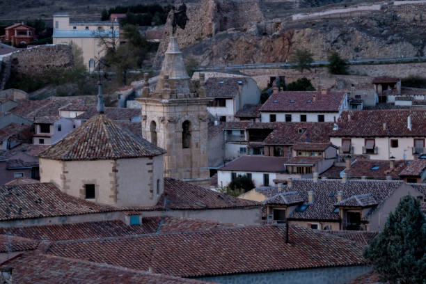 istock Rustic village with ancient stone bell tower and red-tiled roofs surrounded by historic walls at dusk. 2188016890