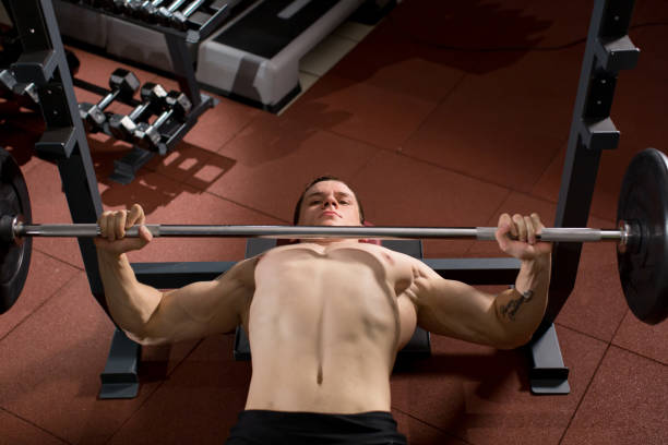 istock Brutal athletic man pumping up muscles on bench press 2188021090