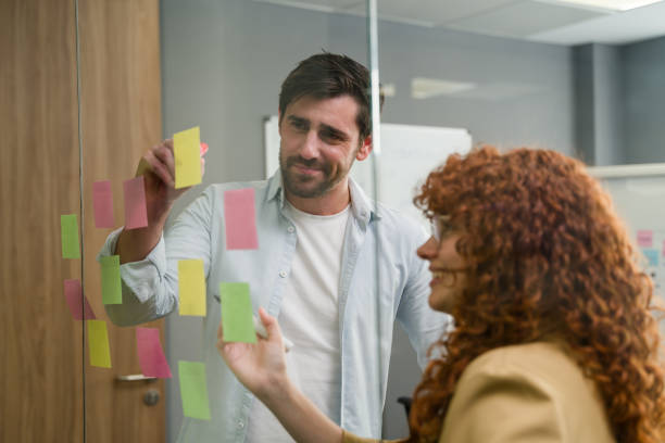 istock Business colleagues brainstorming and planning using sticky notes on glass wall 2188024200