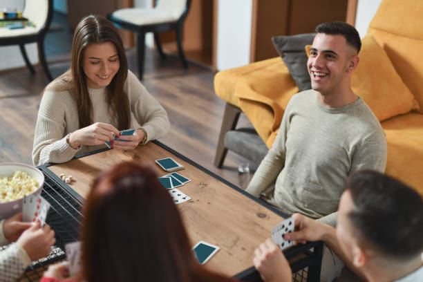 istock Diverse Friend Group Engaging in Fun Card Game Sitting on Ground Around Coffee Table 2188024554
