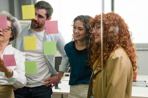 istock Business team brainstorming with sticky notes on glass wall in office 2188024930