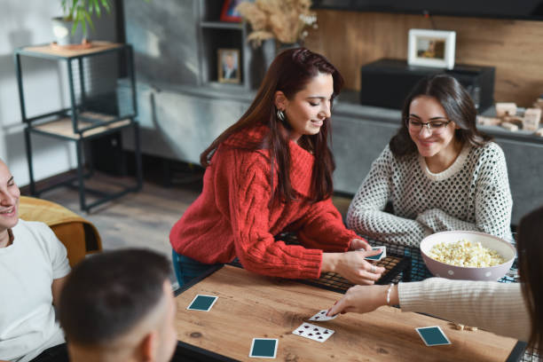 istock Happy Looking Friends Having Fun Night in Playing Cards and Eating Popcorn 2188024992