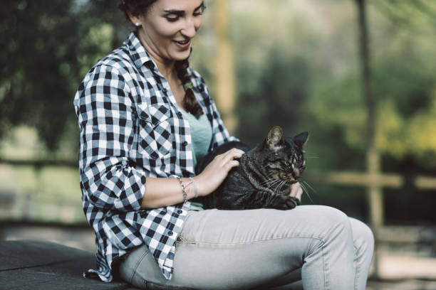 istock Young woman petting a cat outdoors in a park 2188025480