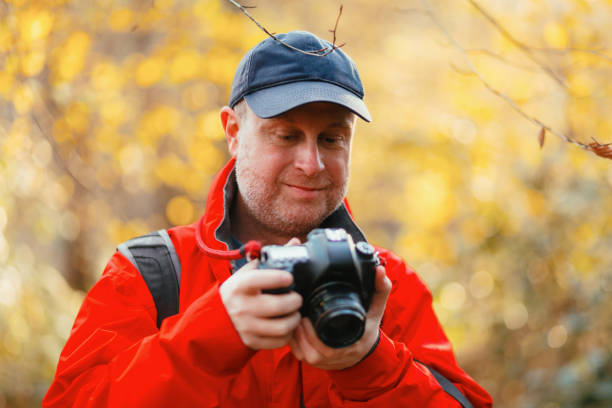 istock Photographer checking LCD screen on camera in golden autumn forest 2188026167