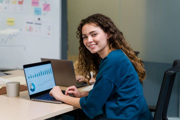 businesswoman analyzing graphs on laptop, working in modern office