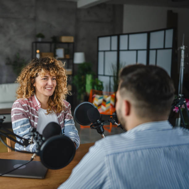 istock woman host interviewer ask man guest questions while record podcast 2188032020
